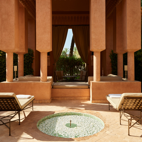 Pavilion bassin at Amanjena with symmetrical terracotta columns framing a central plunge pool and lounge chairs.