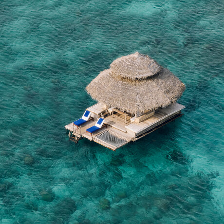 Kawayan bar floating on turquoise waters at Amanpulo resort, Philippines, aerial view.