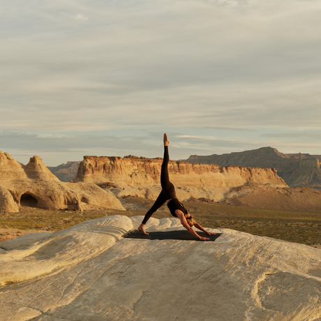 Yoga practitioner in headstand pose on terrace at Amangiri, Utah desert landscape beyond.