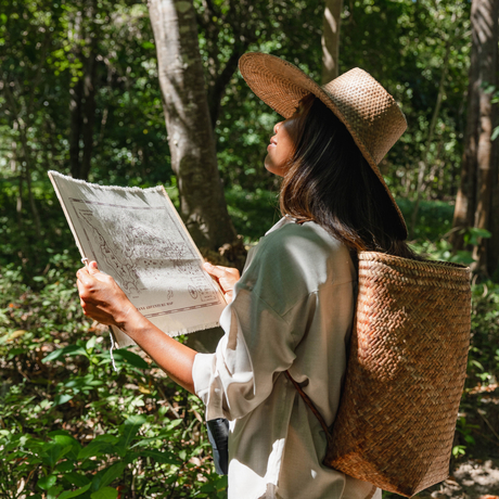 Woman with woven backpack studying a map during a treasure hunt at Amanwana, Sumbawa, Indonesia.