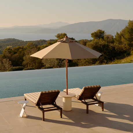 Villa terrace with infinity pool, sun loungers and parasol at Amanzoe resort, overlooking forested hills.