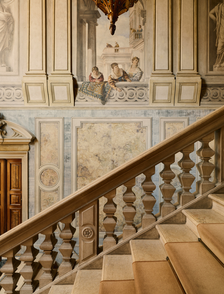Grand staircase with ornate balustrade at Aman Venice, featuring classical architectural details and warm stone tones.