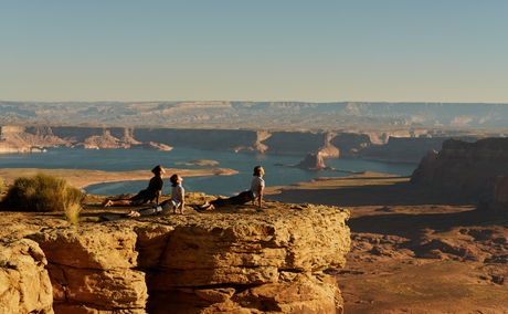 Two people practising yoga on a rocky outcrop overlooking Tower Butte at Amangiri, Utah.