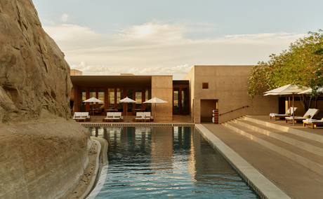 Amangiri's main swimming pool with earthy stone architecture and desert landscape at dusk.