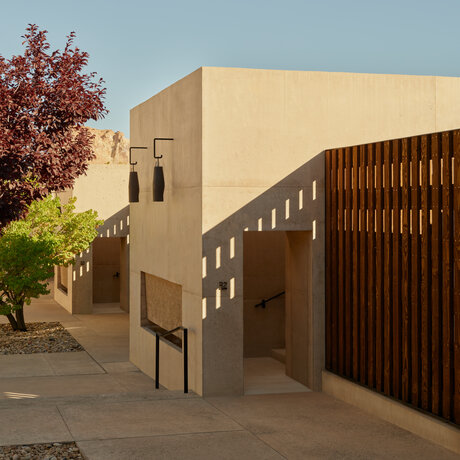 Exterior of Orchard Suite at Amangiri, with cream-coloured walls and wooden screening panels, set against desert landscaping.