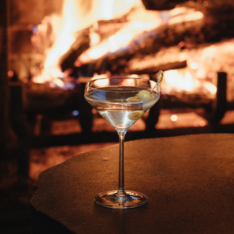 Cocktail glass on table with fireplace glowing in background at Amangani.