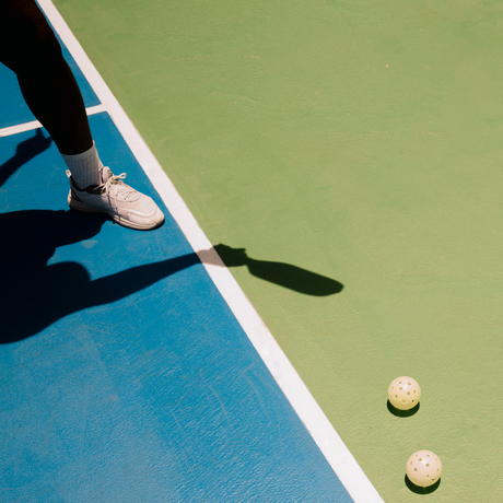 Tennis racquet and balls on blue court at Amanera resort, Dominican Republic.