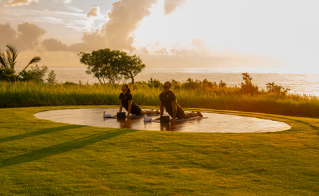 Couple relaxing on expansive green lawn at Amanera resort at sunset.