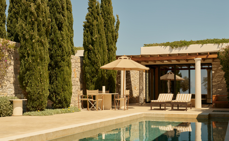 Cabana na praia da Amanzoe, resort à beira-mar com piscina e vegetação mediterrânica.