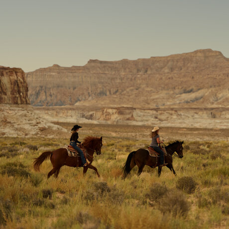 Two riders on horseback crossing the desert landscape at Amangiri, Utah.