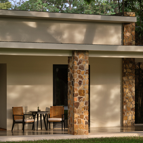 Amansara suite exterior with wooden columns, modern architecture and shaded seating area.