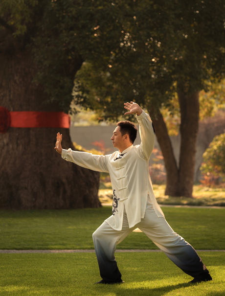 Woman in white shirt practising tai chi on a lawn at Amanyangyun, China, at dusk.