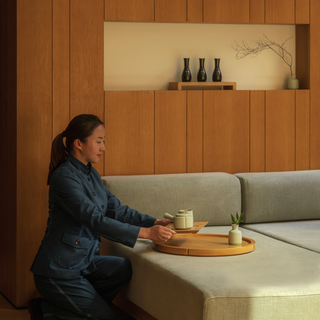 Spa therapist at Amanyangyun Shanghai preparing for a treatment session in a serene wooden-panelled room.