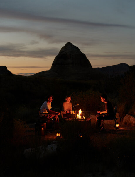 S'mores pavilion at Amangiri at dusk, with fire glowing beneath a desert rock formation.