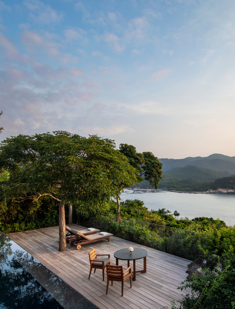 Amanoi accommodation pavilion with dining area overlooking forested coastline and bay in Vietnam.