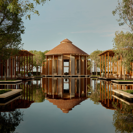 Amanyara's distinctive circular wooden pavilion reflected in still water, surrounded by mangrove trees.
