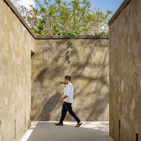 Private butler walking through shaded courtyard at Aman Villas at Nusa Dua, Indonesia.
