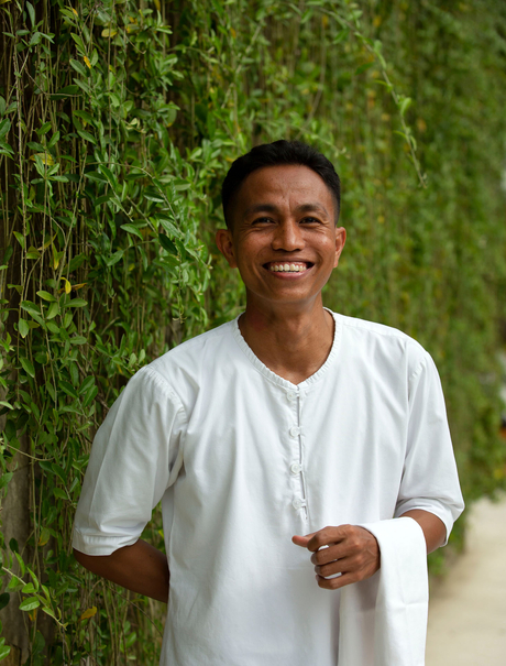 Private butler at Aman Villas at Nusa Dua, Indonesia, standing against vine-covered wall.