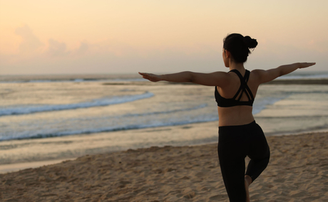 Woman holding surfboard at dawn on Nusa Dua beach, Bali.