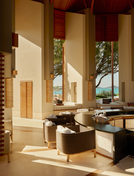 Amanyara bar with wooden accents, natural light streaming through tall windows, and dark furnishings.