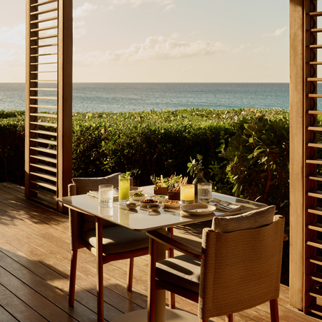 Dining table at Amanyara beach club restaurant with ocean views framed by wooden shutters.