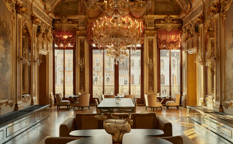 Ornate ballroom at Aman Venice with gilded walls, crystal chandelier, and classical columns.