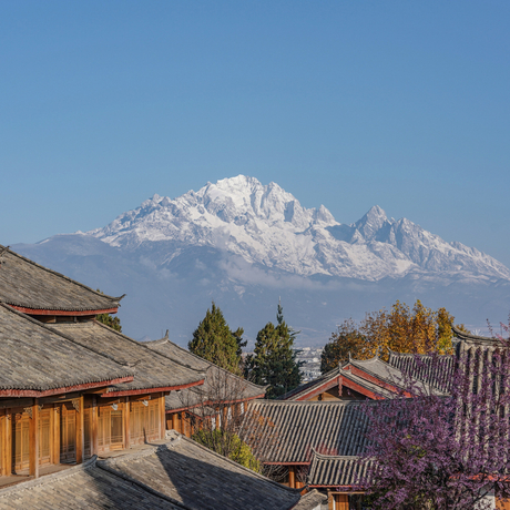 Snow-capped mountain rising above traditional wooden structures at Amandayan in spring.