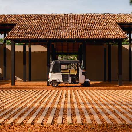Vintage car parked beneath a wooden pavilion with terracotta roof at Amanwella, Sri Lanka.