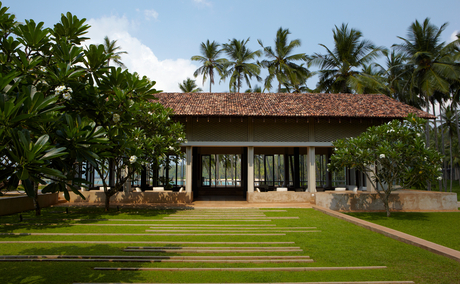 Amanwella lounge pavilion with terracotta roof, surrounded by manicured lawns and tropical palms.