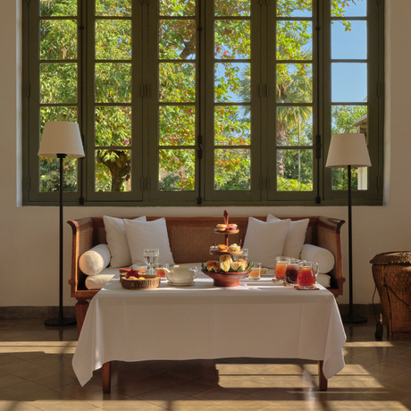 Afternoon tea service laid out on a table in the library at Amantaka, with large windows overlooking verdant gardens.