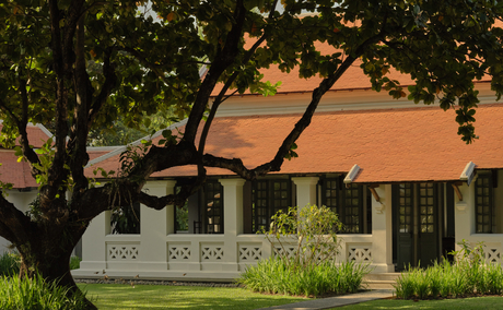 Amantaka's resort exterior corridor with terracotta roof and shaded tree canopy.