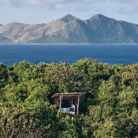 Guide on a nature walk through tropical forest overlooking the sea at Amanpulo resort, Philippines.