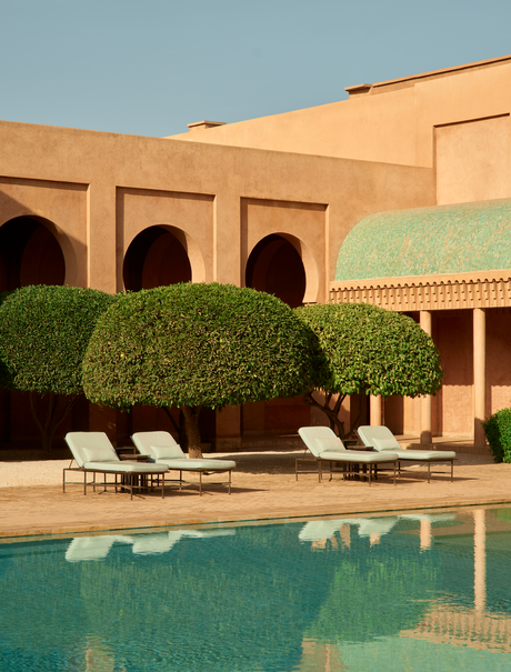 Main pool at Amanjena resort in Morocco, with loungers and ochre-coloured architecture.