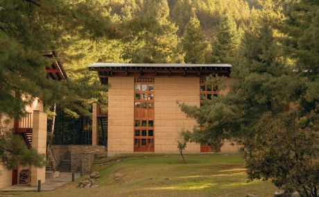 Amankora's exterior in Paro, with a stone building surrounded by dense green forest.