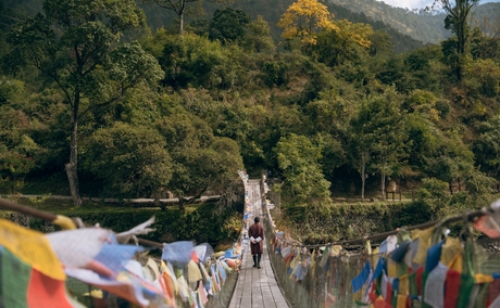 Colourful prayer flags strung across a valley at Amankora in Punakha, Bhutan, with forested mountains beyond.