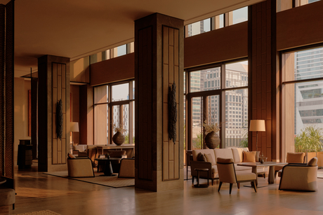 Bar area at Aman Nai Lert Bangkok with warm wood panelling, floor-to-ceiling windows, and mid-century furniture.