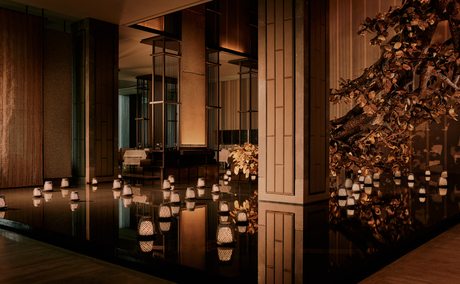 Candlelit spa sanctuary at Aman Nai Lert Bangkok, with warm golden lighting and wooden architectural details.