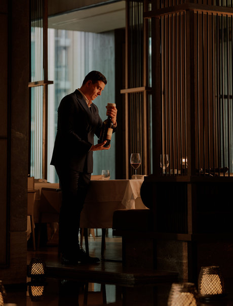 A staff member arranges candles in the entrance hall at Aman Nai Lert Bangkok.