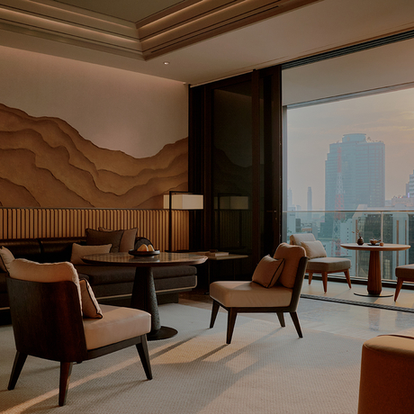 Room 176 at Aman Nai Lert Bangkok with seating area overlooking Bangkok skyline through floor-to-ceiling windows.