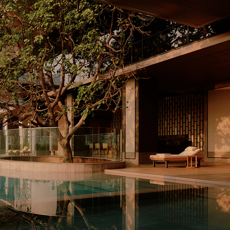 Swimming pool at Aman Nai Lert Bangkok at dusk, with wooden deck and illuminated pavilion.