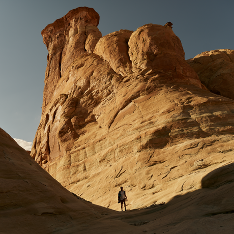 Climber ascending a via ferrata route on a towering sandstone formation at Amangiri, Utah.