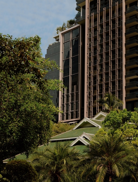 Exterior of Aman Nai Lert Bangkok with vertical timber detailing, framed by tropical greenery.