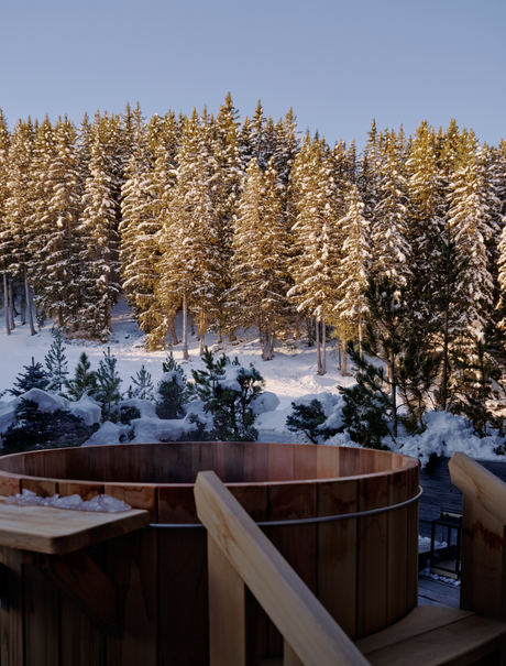 Wooden terrace overlooking snow-covered grounds and frost-laden pine forest at Aman Le Mélézin.