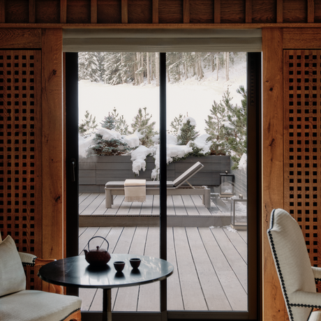 Bedroom with slope views through French doors at Aman Le Mélézin, France.