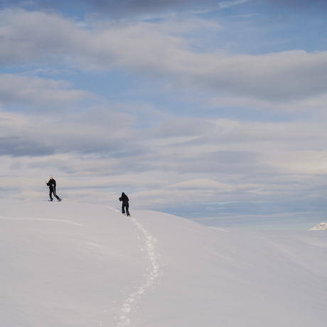 Two snowshoers traversing snowy alpine terrain at Aman Le Mélézin, France.