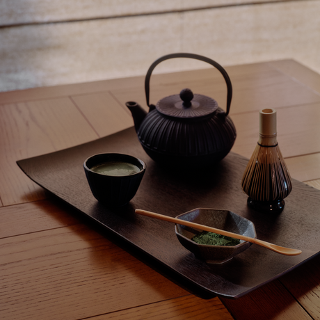 Japanese tea ceremony setup at Aman Le Mélézin with black teapot, cup, and traditional implements on wooden tray.