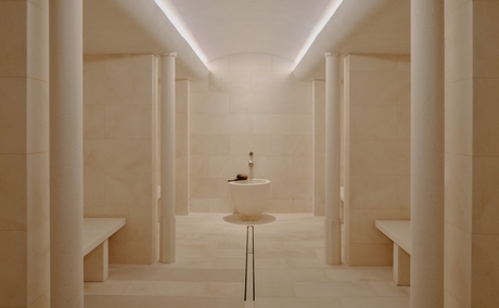 Steam room at Aman Le Mélézin with symmetrical wooden panelling and soft overhead lighting.
