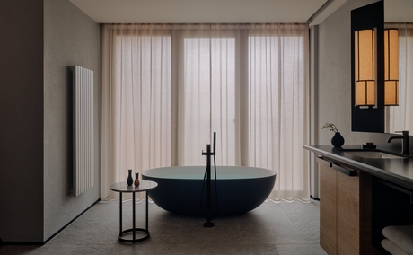 Bathroom at Aman Rosa Alpina with freestanding black basin, floor-to-ceiling curtains, and marble surfaces.