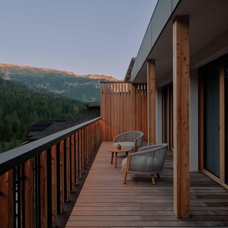Suite terrace at Aman Rosa Alpina with alpine mountain views and seating area at dusk.
