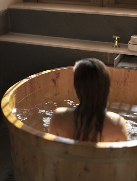Spa treatment detail at Amandayan: guest relaxing in wooden soaking tub filled with water.